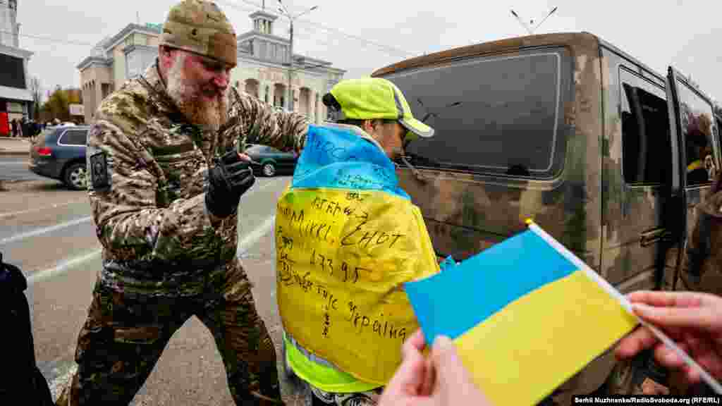 Солдат подписывает украинский флаг в центре Херсона. «Молодежь машет флажками в ритме украинской музыки, — говорит Нужненко об атмосфере в центре только что отвоеванного города, добавляя: — Местные говорят: "Мы вернулись домой, при русских нам ничего не разрешалось, теперь мы снова свободны"»