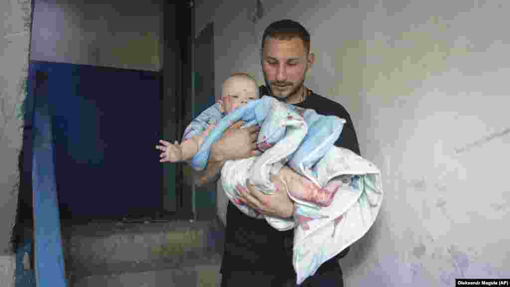 Чоловік виносить дитину із будинку, який був пошкоджений внаслідок російського ракетного удару по Первомайському. 4 липня 2023 року За повідомленнями влади, наймолодшим із 12-ти постраждалих дітей (усього поранення отримали 43 цивільні людини) є 3-місячне немовля.&nbsp;