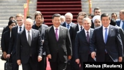 Кытайдын төрагасы Си Цзиньпин (ортодо) менен Шанхай кызматташтык уюмуна мүчө жана байкоочу болгон мамлекеттердин жетекчилери, ошондой эле аймактык жана эл аралык уюмдардын өкүлдөрү 2019-жылы июнда жолугушуу убагында чогуу сүрөткө түшүү үчүн баратышат.