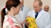 Владимир Путин в родильном доме в Калининграде берет новорожденного ребенка из рук его матери.