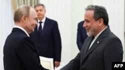 რუსეთის პრეზიდენტი ვლადიმირ პუტინი (მარცხნივ) და ირანის საგარეო საქმეთა მინისტრი აბას არაღჩი ხელს ართმევენ ერთმანეთს კრემლში 23 ივნისს გამართულ შეხვედრაზე.