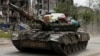 Орус армиясы танкка үй тиричилик буюмдарын жүктөп баратат. Алина Коренюк орус аскерлери анын үйүн тоношконун айтат. Попасна, Луганск облусу, 26-май, 2022-жыл. Бул сүрөт орус күчтөрүнүн Украинага басып киргенден кийинки жоруктарын чагылдырат. 