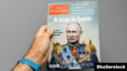 Bir adam ýüzünde Russiýanyň prezidenti Wladimir Putiniň suraty goýlan The Economist žurnalyny tutup dur. Onuň ýazgysy «Patyşa doguldy».  Fransiýa. Strasburg. 2017-nji ýylyň 28-nji oktýabry.